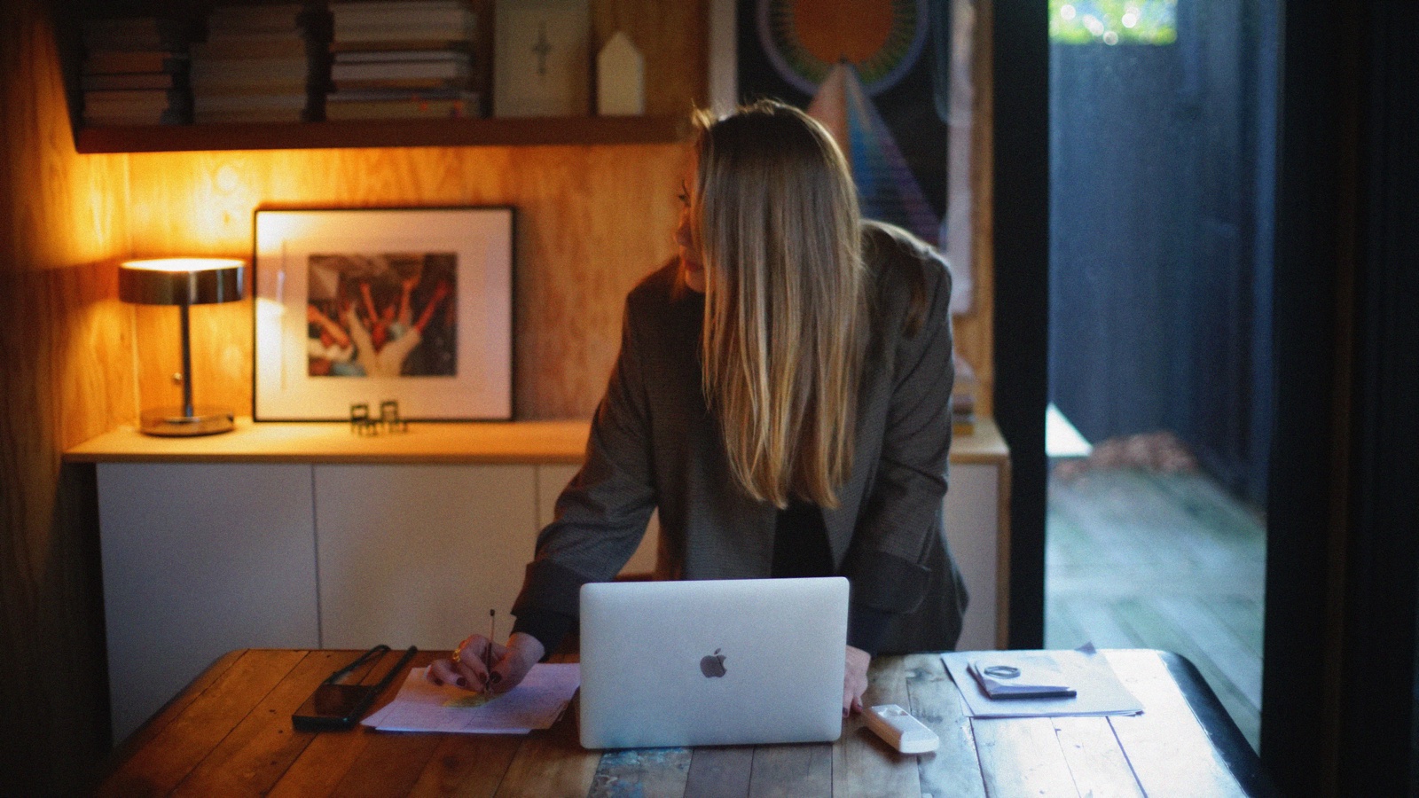 Margot Dandieu à son bureau, dans une lumière chaude, près d’une lampe.