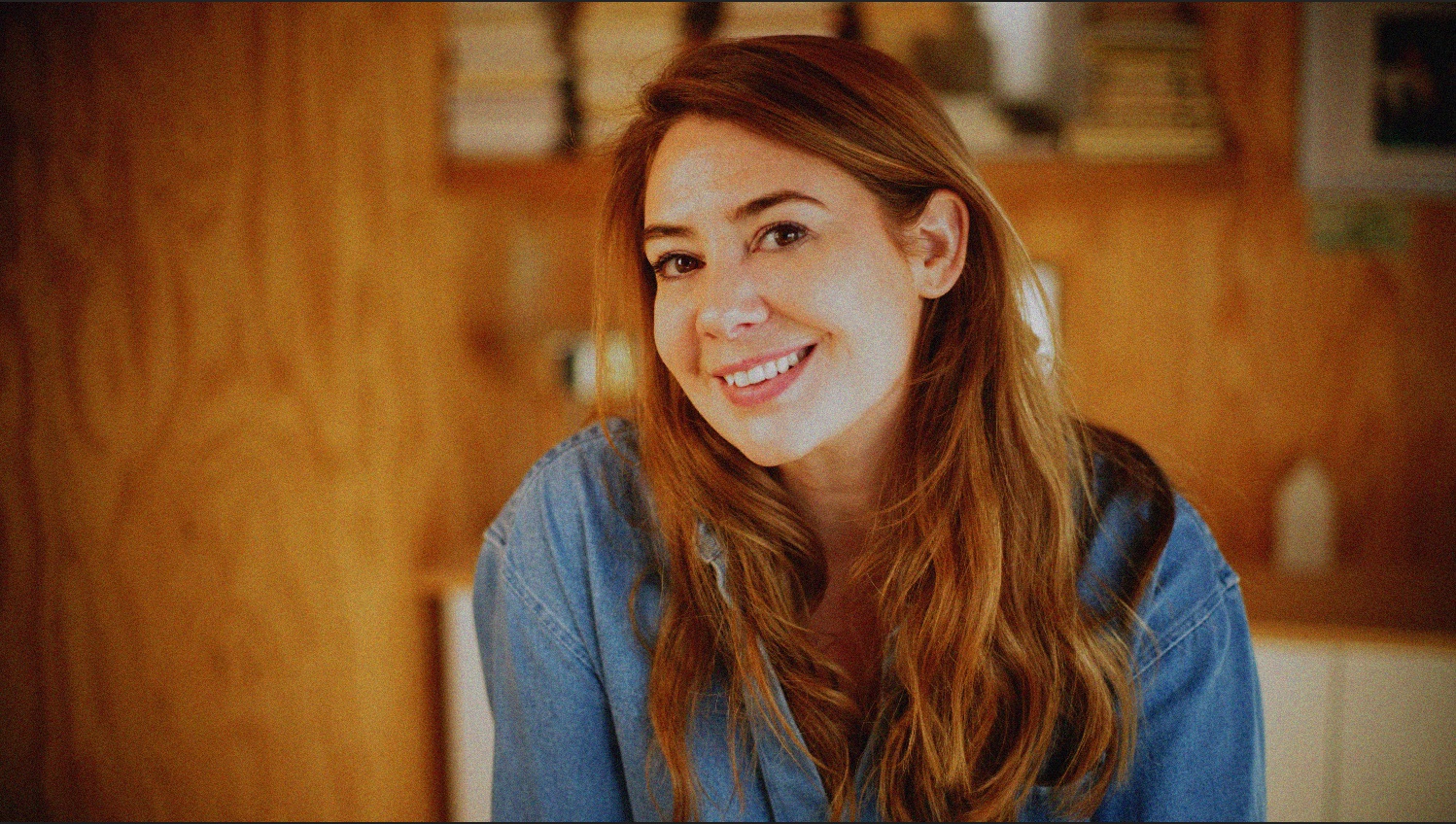 Portrait de Margot Dandieu en chemise en jean, souriante.